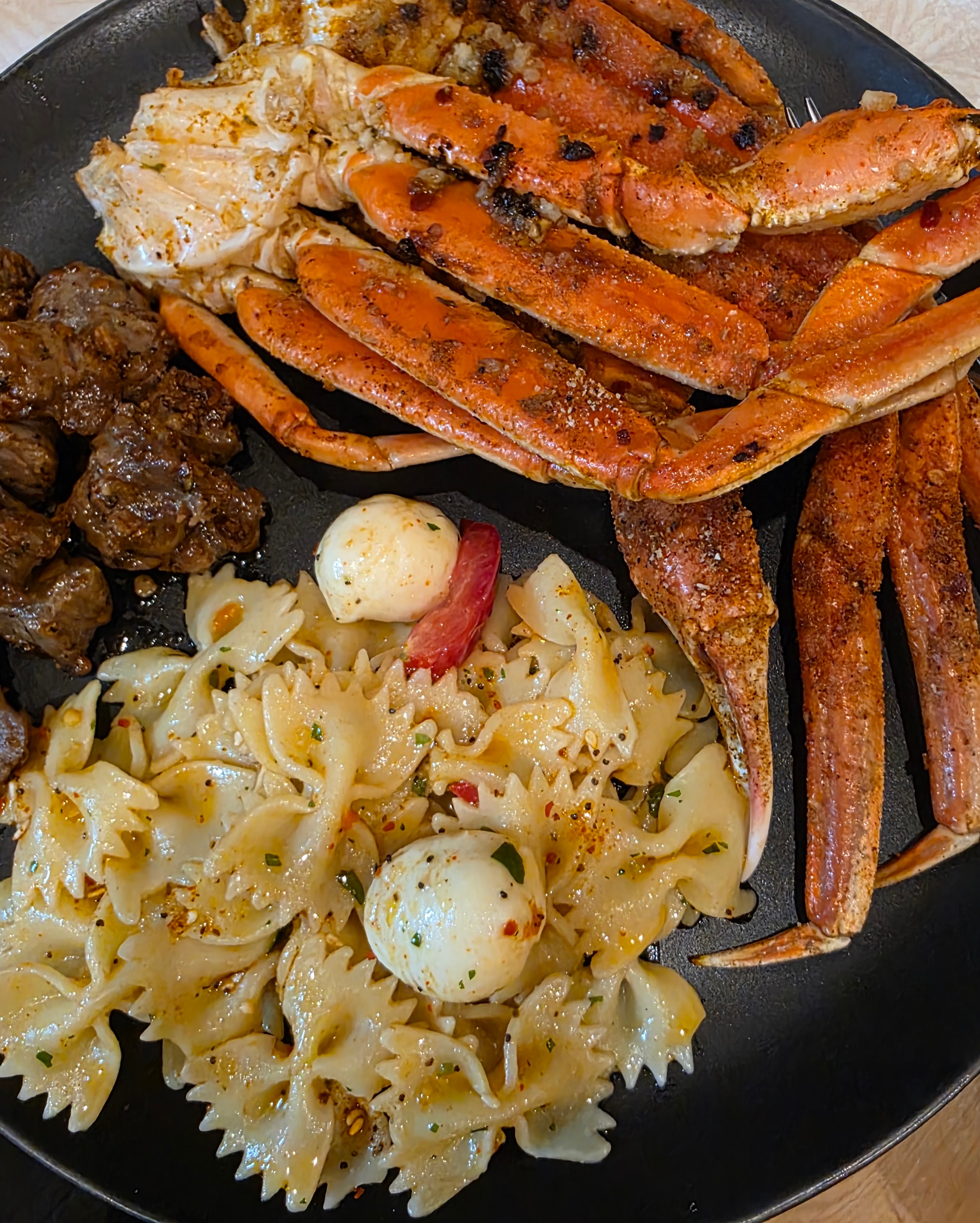 Crab legs with pasta salad and steak bites