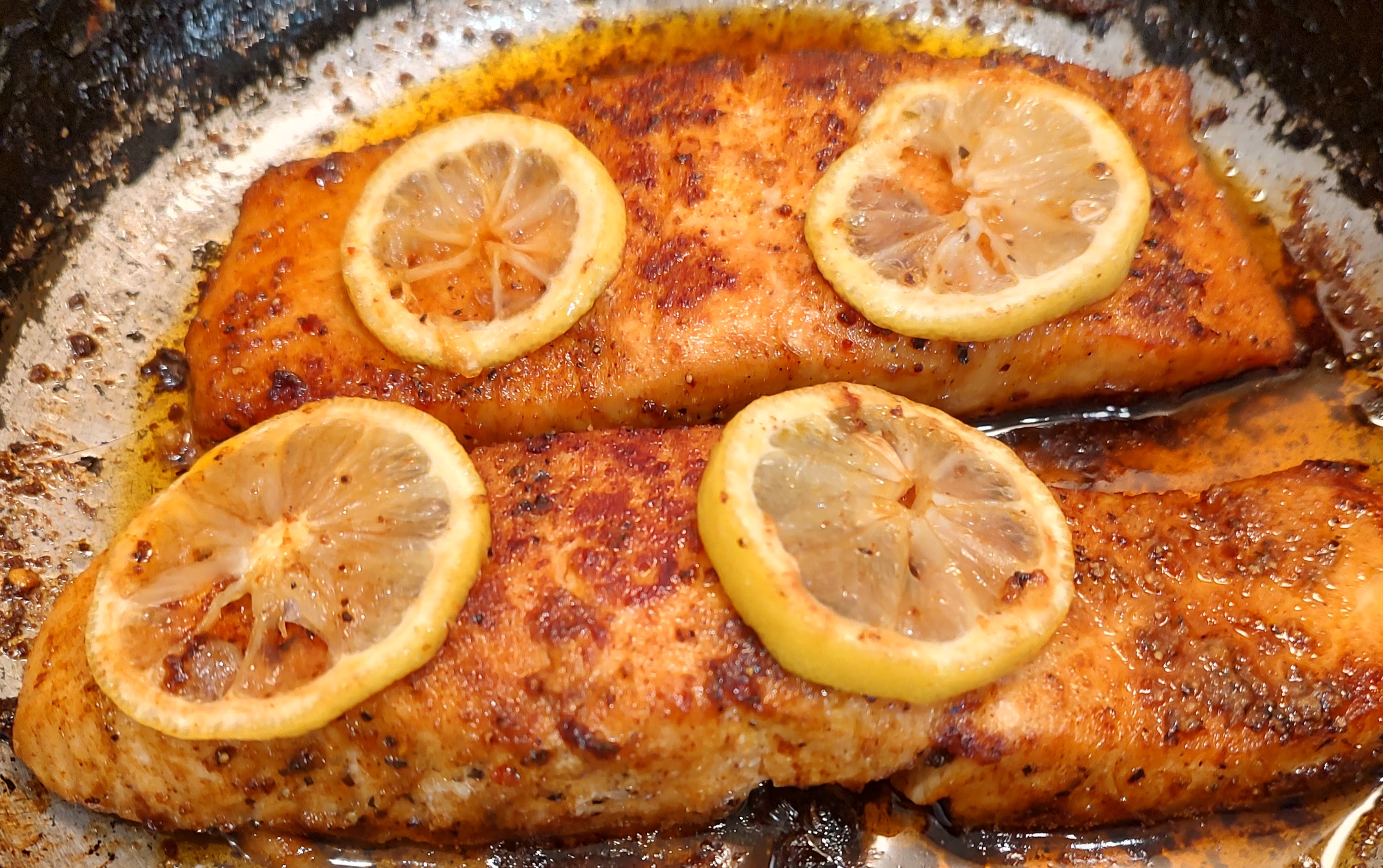 Pan-seared lemon salmon fillets in a skillet