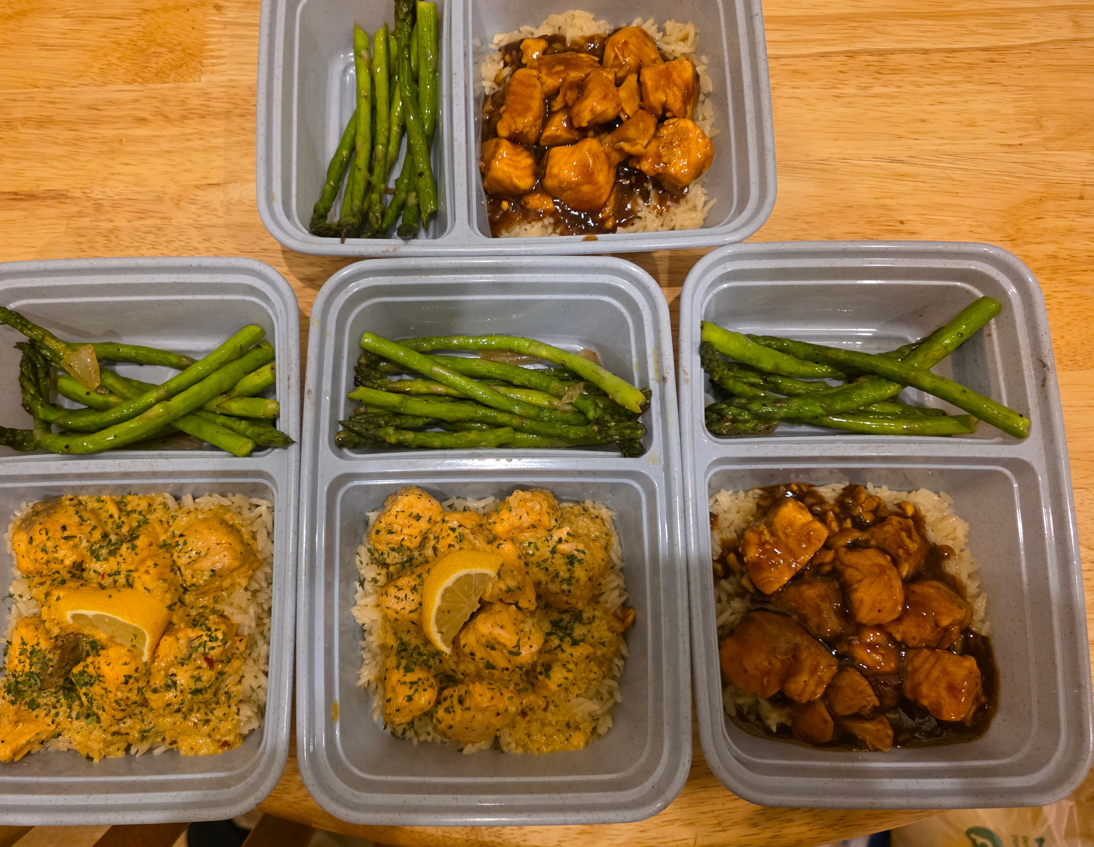 Meal prep containers with lemon chicken, asparagus, and teriyaki chicken over rice