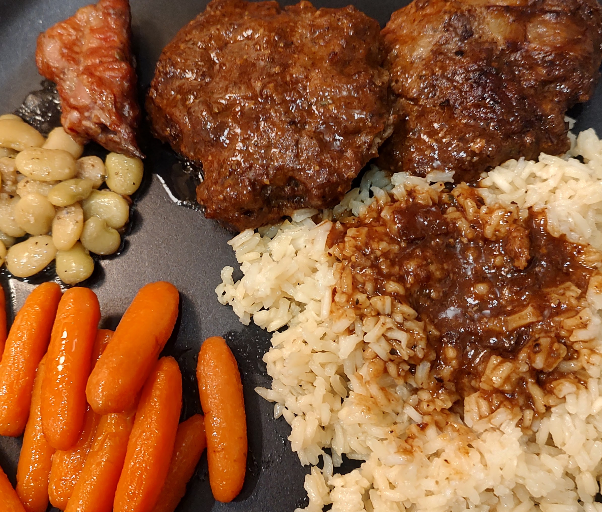 Meatloaf patties with rice, gravy, carrots, and beans